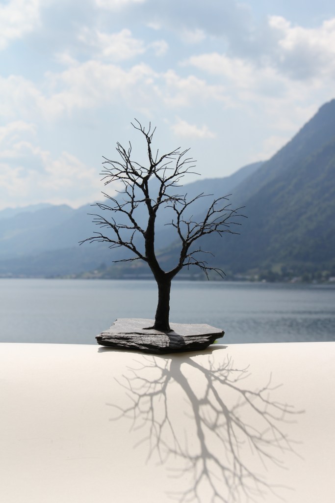 Ein Drahtbaum steht in einer Landschaft.